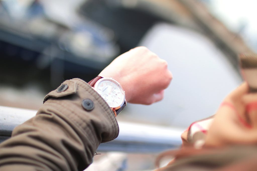 A person checks their wristwatch in a hurried outdoor setting, emphasizing time management.